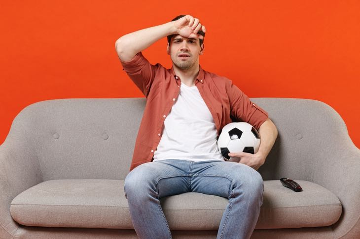 Man holding soccer ball looking worried