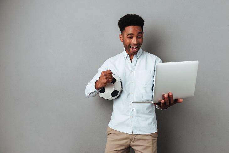 Man with laptop holding football