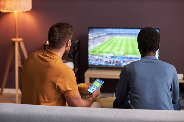 Men watching football at home and placing a bet